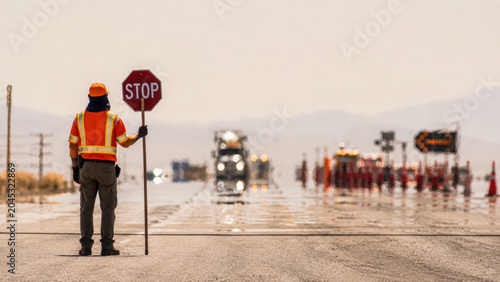 Road construction workers manage traffic with stop sign to ensure safety during heat and stress of work environment
