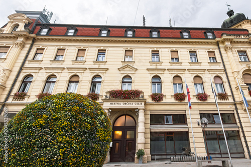 Canvastavla Facade of Mestna Obcina Celje, meaning municipality of celje in slovenian, the city hall and local administration headquarters of Celje, Slovenia, flags, historic architecture, and municipal entrance