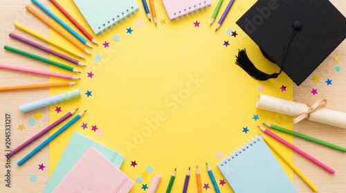 Bright yellow graduation-themed flat lay featuring notebooks, stationery supplies, and academic accessories surrounding a large central copy space. Ideal for student campaigns