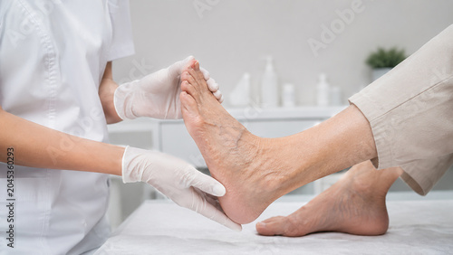 Healthcare professional carefully examines an elderly patient's foot during a medical check-up in a clinic