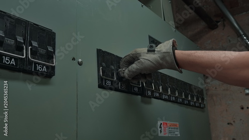 Tableau sur toile Electrician's Gloved Hand Turning Off Circuit Breaker in Electrical Panel