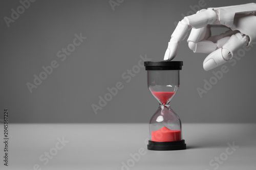 AI humanoid robot finger touching hourglass representing future and deadline.