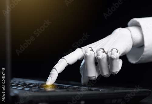 AI humanoid robot finger clicking button on black computer notebook.
