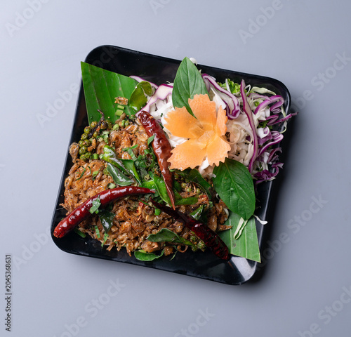 Stir fried crispy small shrimps with herbs on grey background.