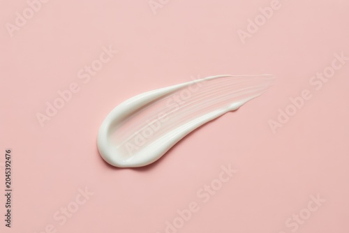 Smooth elegant white cream smudge on a soft blush pink surface showcasing delicate texture and beauty product swatch