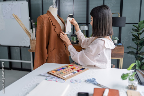 Cuadro en lienzo Asian woman designer selecting fabric samples while creating fashion collection