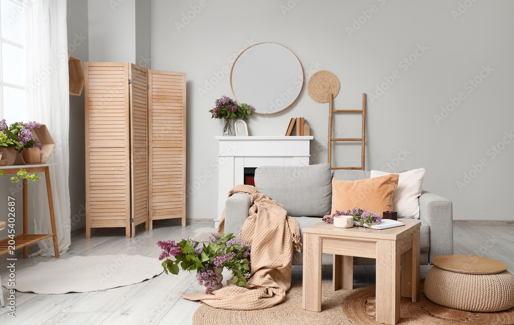 Obraz premium Interior of living room with sofa, mirror and lilac flowers
