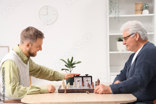 Senior man and his son playing chess at home
