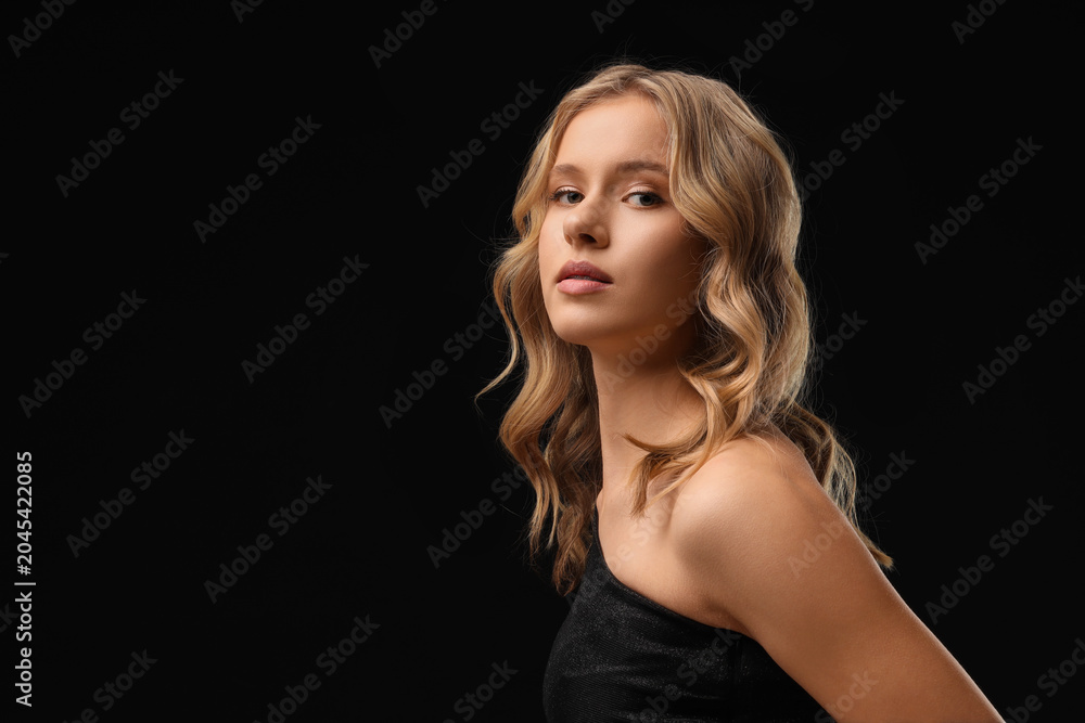 Naklejka premium Blonde young woman with curly hair on dark background