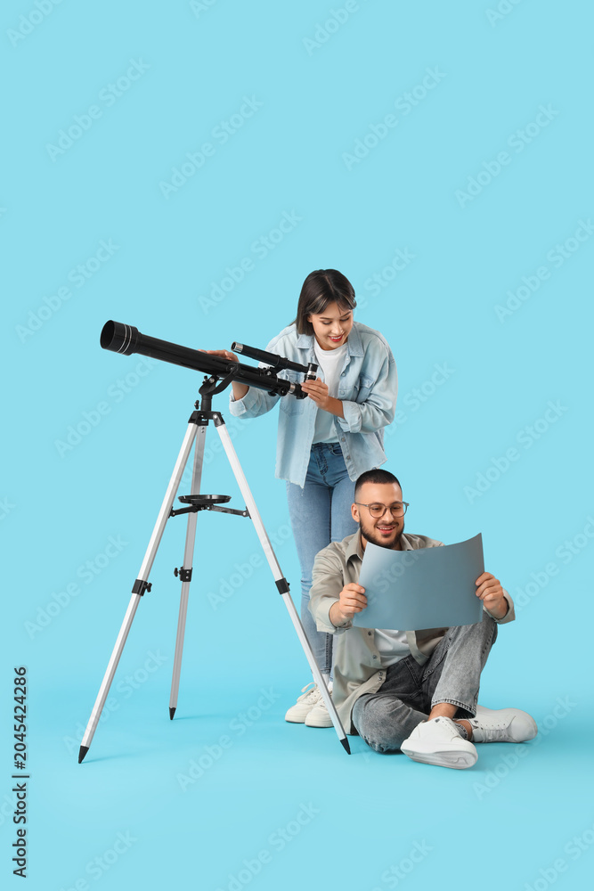 Obraz premium Young couple with telescope and map on blue background