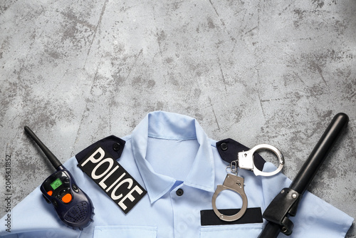 Photos Police officer's uniform, walkie-talkie, baton and handcuffs on grey background