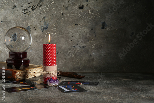 Bild auf Leinwand Magical crystal ball with tarot cards, book and wax candle on grunge grey backgr