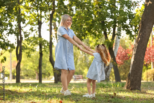 Happy mother with her little daughter having fun in park