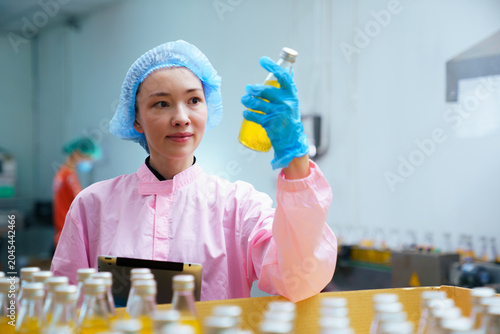 Quality control inspector monitoring juice production line in food factory