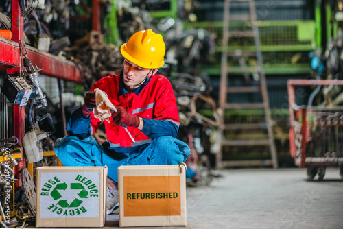 Fotografía Male technician inspecting used auto parts for refurbishing and recycling in scr