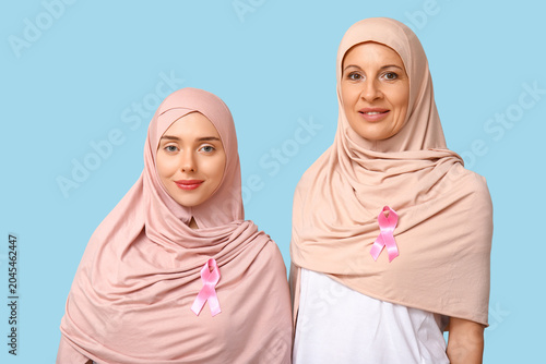 Muslim women with pink ribbons on blue background. Breast cancer awareness co...