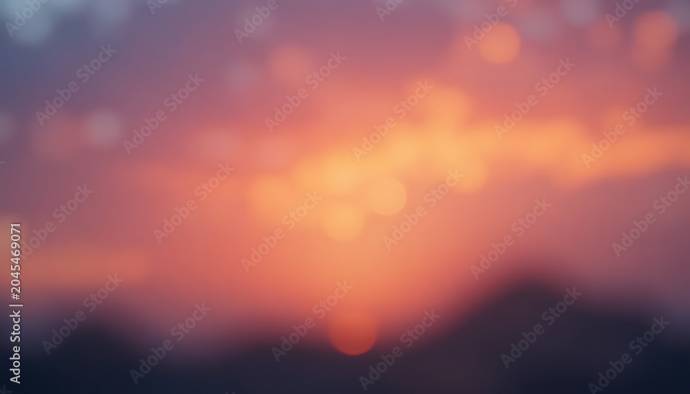 Obraz premium Blurred orange and purple sunset or sunrise with bokeh effect, over mountains or hills