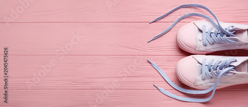 Photos Pair of shoes with untied laces on color wooden background, closeup