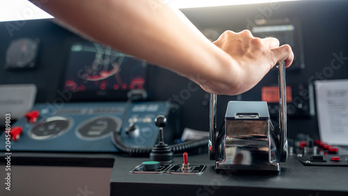 Captain hand holding throttle control or engine control lever on boat dashboard with GPS navigation and marine radar in wheelhouse or ship bridge. Speed adjustment instrument for seafaring technology