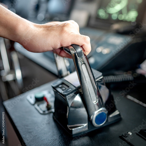 Obraz na plátně Captain hand holding throttle control or engine control lever on boat dashboard with GPS navigation and marine radar in wheelhouse or ship bridge