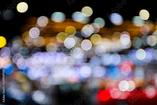 dense bokeh from a crowded car expo. lots of bright white and golden blurry lights mixed with red at the bottom