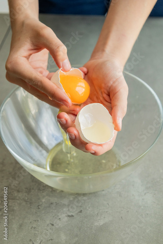 Close-up of a child's hands carefully separating an egg yolk from the egg white using their fingers over a bowl