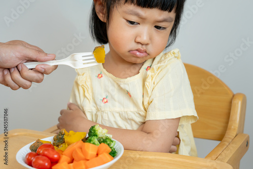 Fotografie Children confuse to eat vegetables, bitter taste, peculiar smell, unattractive a