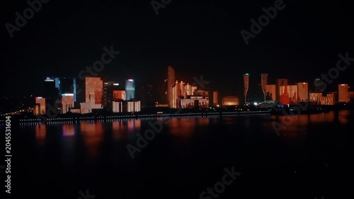 Illuminated Modern City Skyline Reflected on Calm Waterfront at Night