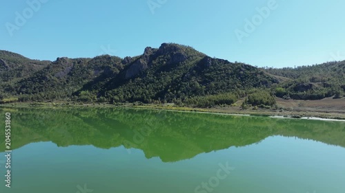 Mountain Lake Reflection with Forested Hills and Clear Blue Sky