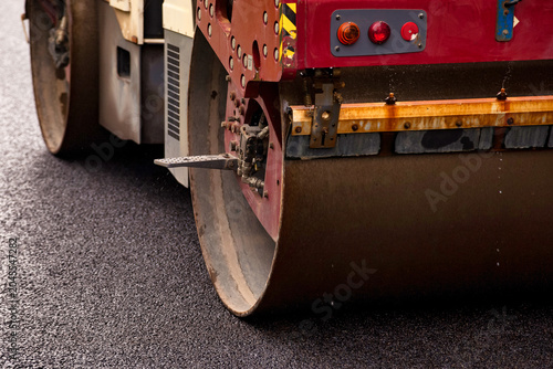 Schilderij op canvas Heavy machinery is actively paving asphalt on a street road, showcasing urban construction efforts