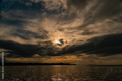 Bild auf Leinwand Dramatic Orange Twilight Sky Over Sea and Mountain Silhouettes