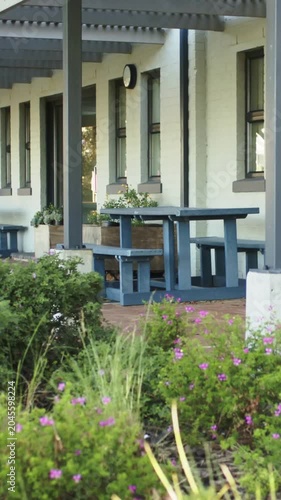 Vertical video: Panning camera focusing on blue picnic table with bench on porch, for quiet seating
