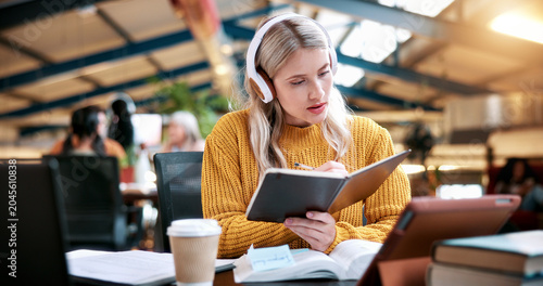 Картината върху платно Student, reading and book with headphones in library for higher education, learning or studying