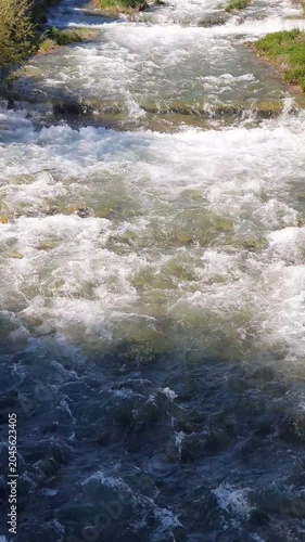 Melting snow in the mountains, fast streams of cold clear ice water flow through thawed snow on rocks in Bulgaria.