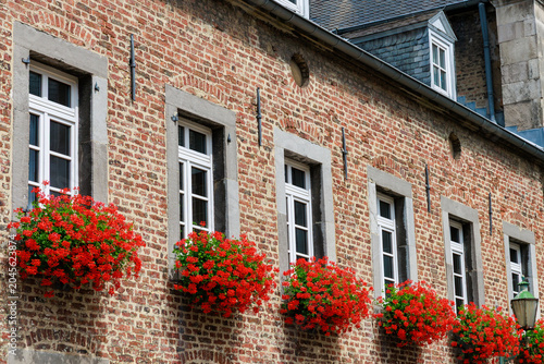 Fotografie Historic brick building facade with red flower boxes beneath white windows
