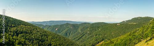 Foto Extensive panoramic view of forested green mountain ridges and distant blue hill