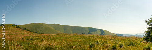 Rolling green hills of Velka Fatra national park in Slovakia under clear sky with distant mountain silhouettes