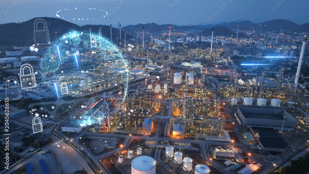 Obraz premium Glowing digital globe and security padlocks overlaid on a petrochemical refinery plant at night. Industrial cybersecurity, OT network protection, and global energy infrastructure defense.