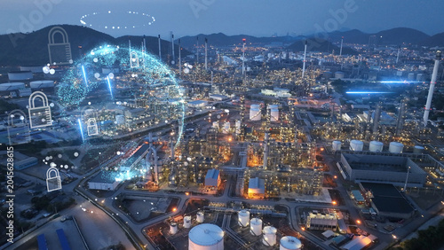 Glowing digital globe and security padlocks overlaid on a petrochemical refinery plant at night. Industrial cybersecurity  OT network protection  and global energy infrastructure defense.