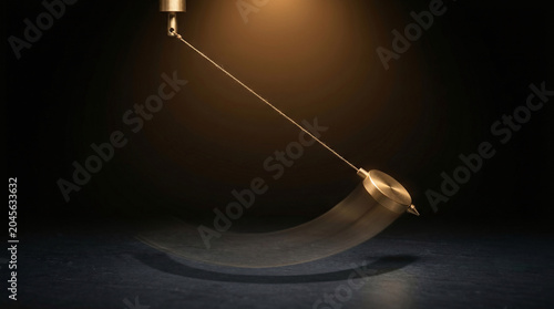 Swinging brass pendulum captured with motion blur against a dark background