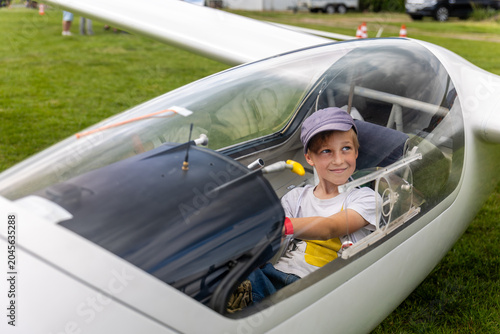 Cuadro en lienzo Cute little happy boy sits inside glider cockpit aviation club activity airfield