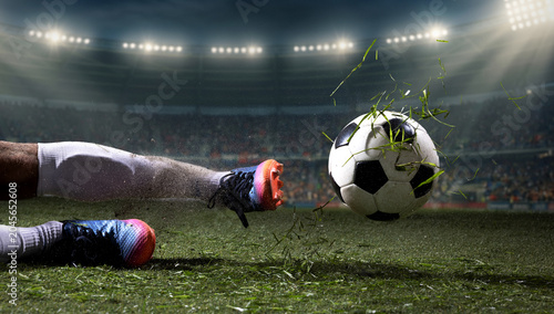 Obraz na plátně Soccer player sliding after ball with flying grass in night stadium