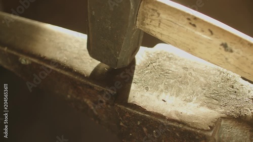 Close-up of an iron hammer with a wooden shaft resting on an anvil, highlighting rustic craftsmanship and blacksmithing details.