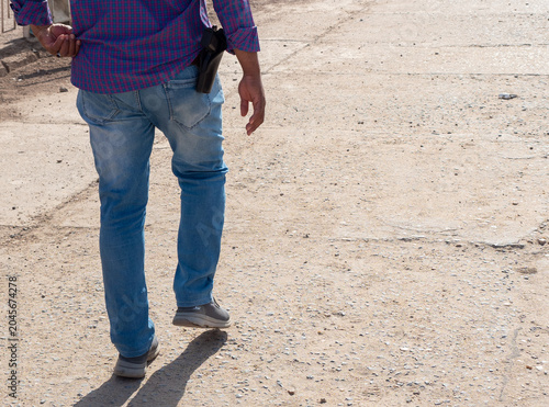 Obraz na płótnie Man walking carrying handgun in a holster on dry ground