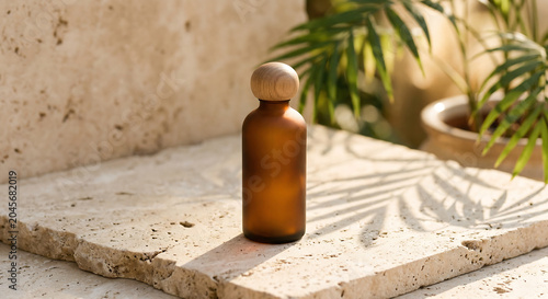 Brown bottle stands on stone surface beside green plant.