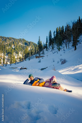 Man relaxing on fresh snow in a sunny mountain landscape during winter in Kashmir, India