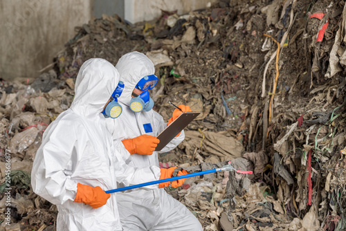 Fotografie Expert Team Inspecting Hazardous Waste with Equipment: Image of a expert team in full protective suits, respirators operating in a hazardous waste environment