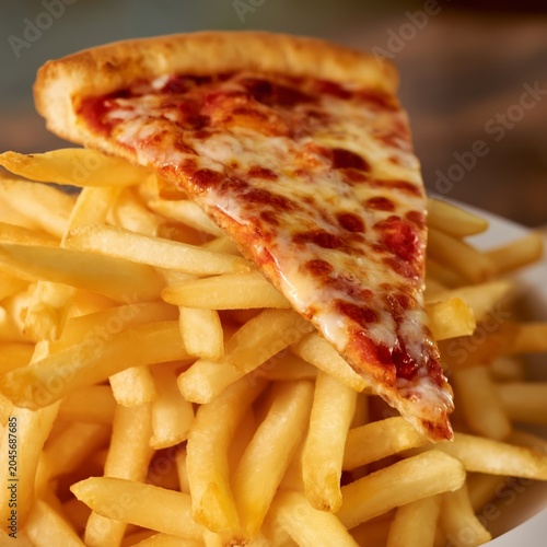 Pizza Slice on Top of a Large Stack of French Fries Served in a Restaurant Se...