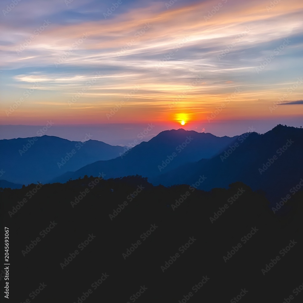 Obraz premium Mountains and Clouds at Sunset in a Clear Sky With Vibrant Colors of Orange and Blue