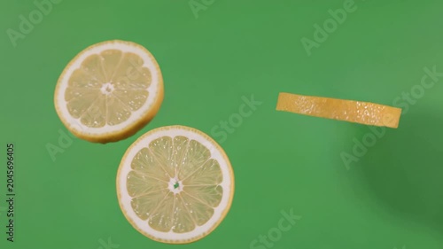 Freshly cut yellow lemon slices slowly falling and rotating in the air against a vibrant green background. Concept of healthy eating and vitamins